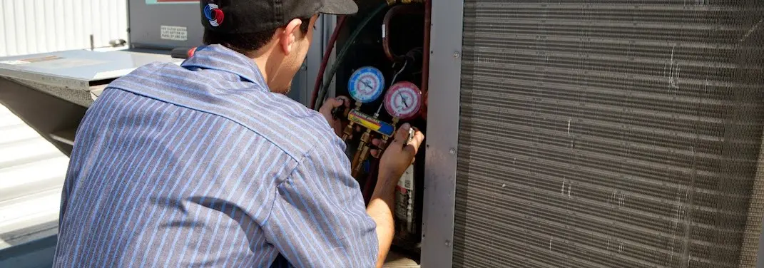HVAC technician servicing a condenser unit in Lihue